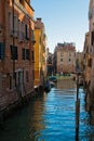 Narrow canal among old colorful brick houses in Venice, Italy
