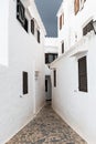 Narrow cobble stone street between white solid buildings