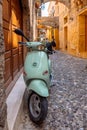 Narrow cobbled historical streets of Rhodes. Tourists walk on Old Town. Vintage scooter bike is parked old stone against