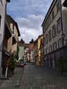 Narrow cobblestone alley in historic center of Esslingen with parking cars, old buildings and old castle on the hill.