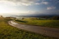 Narrow concrete road with a view of field and mountains under the cloudy sky