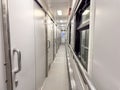 a narrow corridor inside a modern train car, with closed compartment doors on one side and large windows on the other Royalty Free Stock Photo