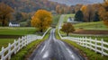 A narrow country road winds through fields and pastures, with majestic trees and white fences along the sides in Midwest