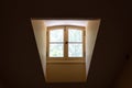 Narrow dormer window as seen from the inside of a darkened room with sunlight streaming in