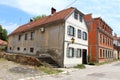 Narrow elongated old dilapidated suburban family house with cracked facade and renovated front side next to newly built house