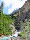 A narrow fast moving river running down through a steep valley high in the Rockies along the Berg Lake Trail