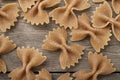 Narrow focus closeup of whole wheat farfalle pasta over wooden table Royalty Free Stock Photo