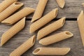 Narrow focus closeup of whole wheat penne pasta over wooden table Royalty Free Stock Photo