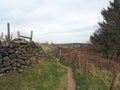 Narrow footpath between a dry stone wall and fence surrounding a meadow in west yorkshire countryside near heptonstall Royalty Free Stock Photo