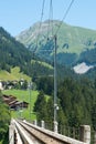 Narrow gauge railroad tracks lead over a long bridge in the Swiss Alps near Arosa