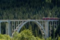 Narrow gauge train crosses a long viaduct across a deep canyon in the Swiss Alps Royalty Free Stock Photo