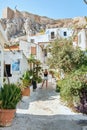Narrow greek street with many plants and houses on the mountain and a girl in a hat. Passion for travel and tourism.