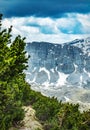 Narrow hikers pathway high in mountains and heavy clouds in the sky Royalty Free Stock Photo