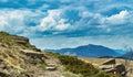 Narrow hikers pathway high in mountains and heavy clouds in the sky Royalty Free Stock Photo