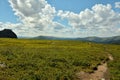 A narrow hiking trail, skirting a rocky clearing, descends from a high hill into a mountain valley on a cloudy summer day Royalty Free Stock Photo