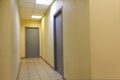 A narrow light corridor in the office room with a few gray doors