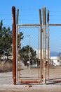 Narrow locked doors made from wire fence and strong rusted metal frame with barb wire on top