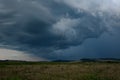 Narrow long vertical lightning bolt shoots out of a dark thundercloud