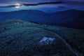 narrow meadow path in grass among white stones on top of the hill in high mountain at night. Royalty Free Stock Photo