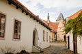 Narrow medieval street with baroque and renaissance historical buildings, sunny summer day, gothic clock tower of Town hall with