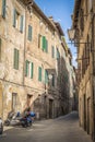 A narrow medieval street with brick houses, lanterns and motorcycles in Siena, Italy Royalty Free Stock Photo