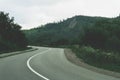 A narrow mountain road winding into dense dark green coniferous forest. A winding path among mountains and hills Royalty Free Stock Photo