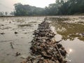 A narrow muddy dirt road has gone through the middle of the waterlogged farmland an both sides