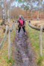 Narrow muddy path between fences with mature woman trying to walk