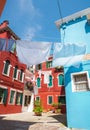 Narrow old Burano island streets with colorful houses and hinged drying linen, Venice, Italy. Very attractive famous travel