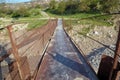 A narrow old rusty river crossing . Dirty, stony river . a suspension bridge still made of an iron stand was used to cross the Royalty Free Stock Photo