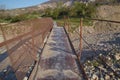 A narrow old rusty river crossing . Dirty, stony river . a suspension bridge still made of an iron stand was used to cross the Royalty Free Stock Photo