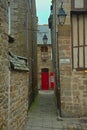 Narrow passage between two traditional stone buildings with red entrance door ahead Royalty Free Stock Photo