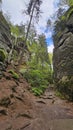 Narrow path flanked by towering rock formations covered with patches of moss and greenery Royalty Free Stock Photo