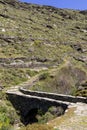 Narrow path and stone old bridge in the mountains Cyclades, Andros Island, Greece Royalty Free Stock Photo