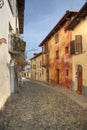 Narrow paved street among houses in Saluzzo.