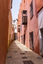 Narrow pedestrian alley leading through tall colorful pink houses