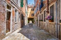 Narrow pedestrian cobblestone old alleys in Venice, Italy. Old worn out medieval buildings