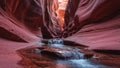 Red sandstone canyon with water trickling through narrow passage under diffuse light
