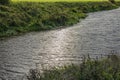 Narrow river meanders through fields against backdrop of vibrant sunset. Royalty Free Stock Photo