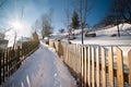 Narrow road covered by snow at countryside. Winter landscape with snowed trees, road and wooden fence. Cold winter day at village
