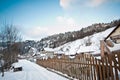 Narrow road covered by snow at countryside. Winter landscape with snowed trees, road and wooden fence. Cold winter day at village