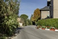 A narrow road that ends in a passage between trees and hedges next to some urban residential buildings Royalty Free Stock Photo