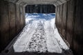 A narrow snow-covered country road in a concrete tunnel.