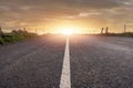 Narrow straight asphalt road with white road markings at sunset. Dramatic sky. Nobody. Low angle of view. Travel concept Royalty Free Stock Photo