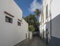 Narrow street in Agaete city center with traditional architecture, old white houses in colonial style, stone wall and Royalty Free Stock Photo