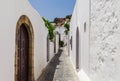 Narrow street in Lindos town on Rhodes island, Dodecanese, Greece. Beautiful scenic old ancient white houses with flowers. Famous Royalty Free Stock Photo