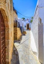 Narrow street in Lindos town on Rhodes island, Dodecanese, Greece. Beautiful scenic old ancient white houses with flowers. Famous Royalty Free Stock Photo