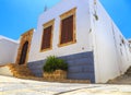 Narrow street in Lindos town on Rhodes island, Dodecanese, Greece. Beautiful scenic old ancient white houses with flowers. Famous Royalty Free Stock Photo