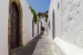 Narrow street in Lindos town on Rhodes island, Dodecanese, Greece. Beautiful scenic old ancient white houses with flowers. Famous Royalty Free Stock Photo