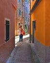 Narrow street with lonely person and colorful old buildings in old small village Montemarcello in Liguria, Italy